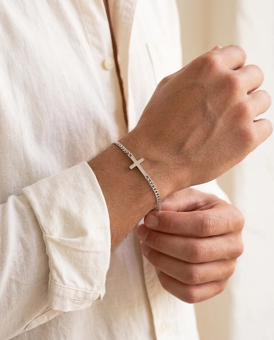 Man adjusting the cuff of a white linen shirt, wearing a silver Stellan sideways-cross bracelet